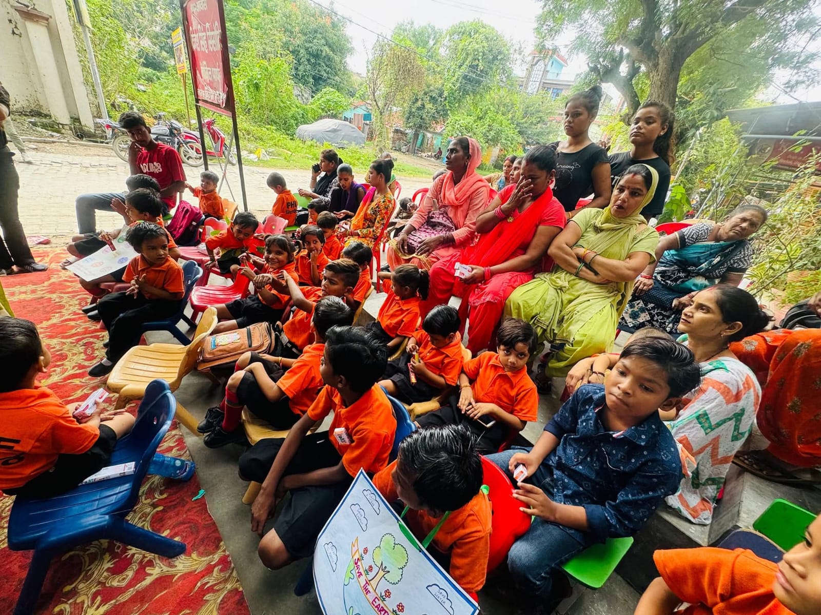 Children sitting in a circle outdoors displaying Save the Earth drawings